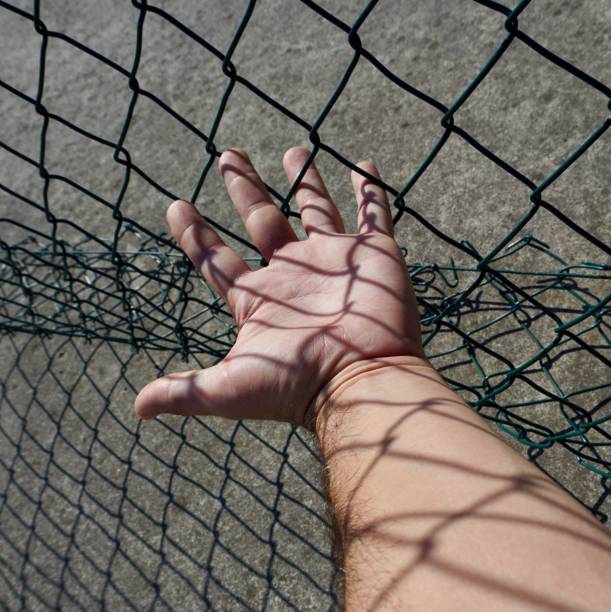 istock hand grabbing a metallic fence 1183341452