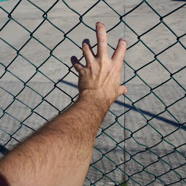 istock hand grabbing a metallic fence 1183341476