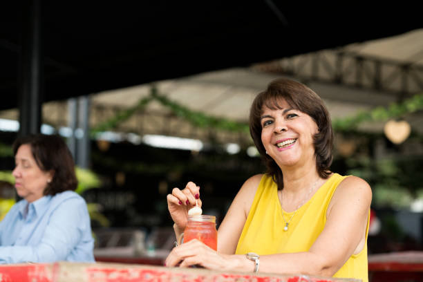 portrét starší ženy popíjející v džusu v restauraci - dobrovolná skromnost životní styl fotky - stock snímky, obrázky a fotky