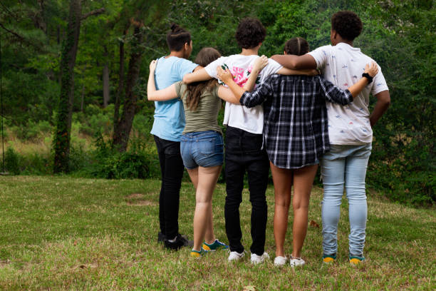 istock Multi-ethnic teen group in a group hug backs facing camera 1183346954