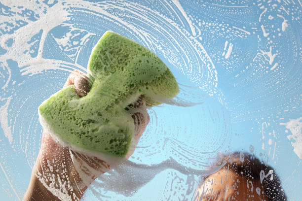Window cleaner using a sponge and soap suds to wash a window