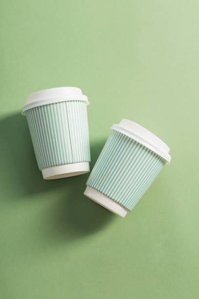 istock disposable paper cup with coffee on green background 1183349459
