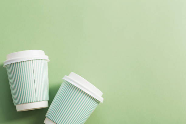 istock disposable paper cup with coffee on green background 1183349462