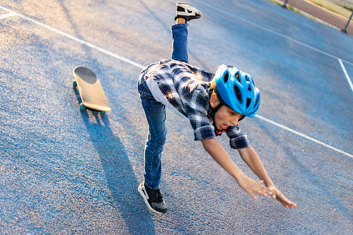 istock Schoolboy with a helmet falling from his skateboard 1183349848