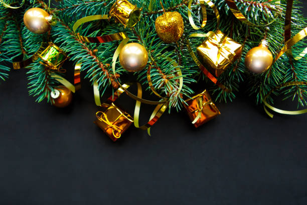 istock Christmas tree branches with golden decorations on black background. Top view, banner, copy space for the text. Beautiful Xmas greeting card 1183350893