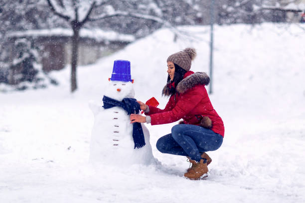 istock Woman  playing with a snowman on winter day. 1183351369