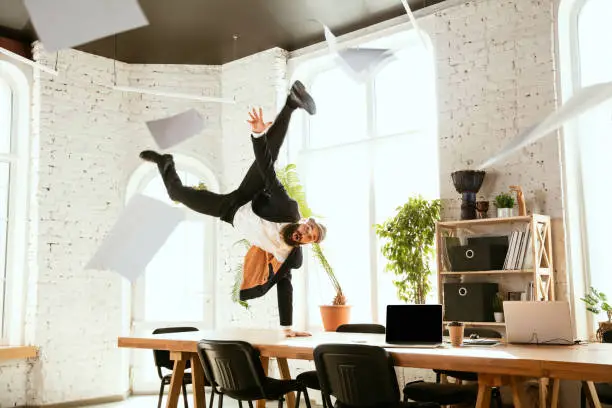 Photo of Businessman having fun dancing break dance in the office at work