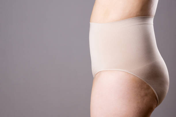 женщина в корректирующих трусиках, избыточный вес женского тела в shapewear на сером фоне - overweight tummy tuck abdomen body стоковые фото и изображения