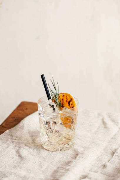 Gin Tonic Gin tonic garnished with charred orange and lavender, on a rustic table gin tonic stock pictures, royalty-free photos & images