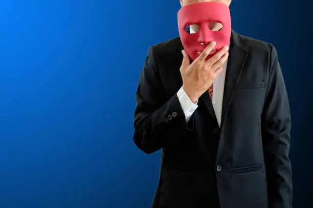 The man hold red mask in hand on blue background with clipping path.