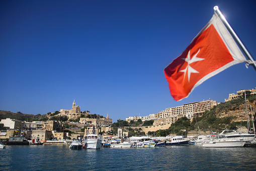Maltese flag in front of Mgarr harbour on Gozo island on Malta.