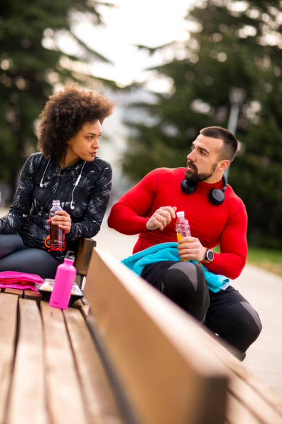 istock Young athletic couple hydrating themselves while taking a break after exercising in a city park 1183366481