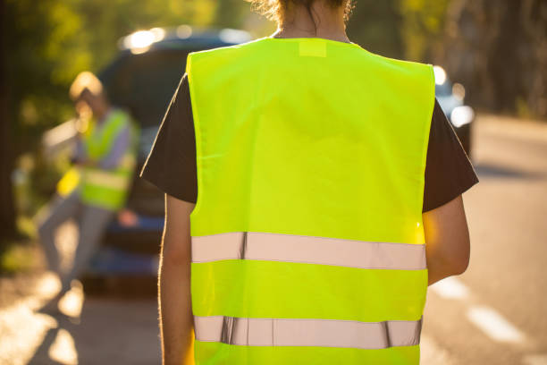 Roadside assistance is here Rear view of auto mechanic coming to help young woman with her car problem, wearing fluorescent waistcoats reflective clothing photos stock pictures, royalty-free photos & images