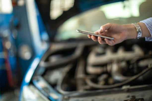 istock Unrecognizable woman using phone in auto repair shop 1183369131