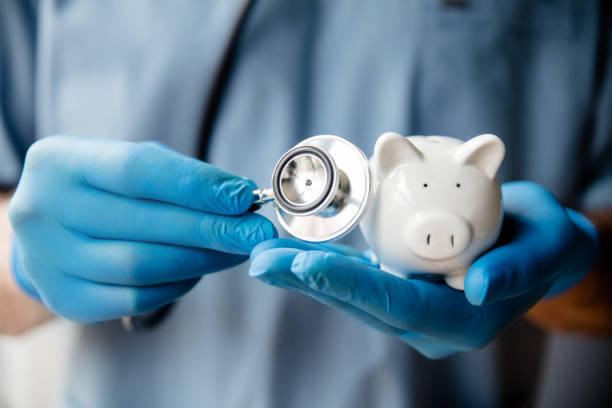 Doctor holding stethoscope to piggy bank stock photo