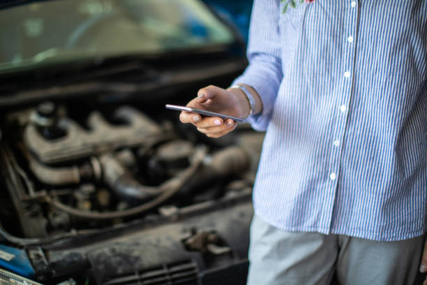 istock Unrecognizable woman using phone in auto repair shop 1183370068