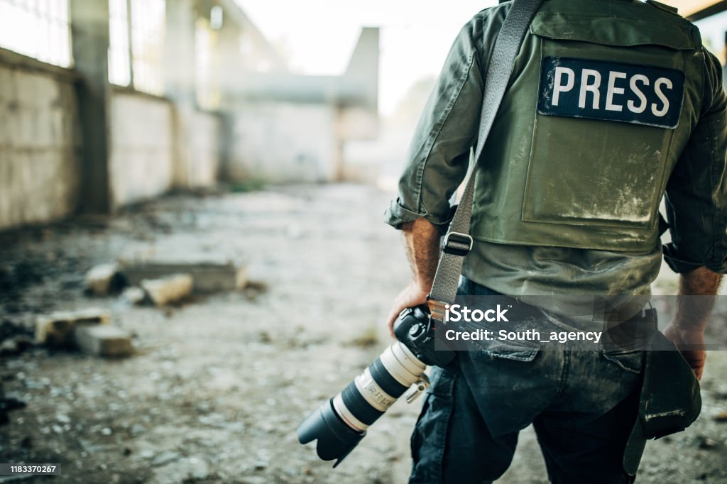 Man war journalist with camera One man, war journalist with digital camera at the place of action, in war zone. Journalist Stock Photo