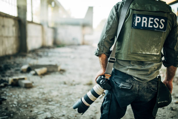 Man war journalist with camera One man, war journalist with digital camera at the place of action, in war zone. newscaster photos stock pictures, royalty-free photos & images