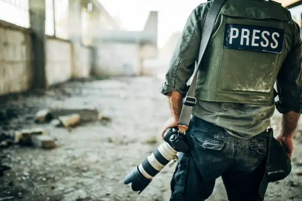 One man, war journalist with digital camera at the place of action, in war zone.