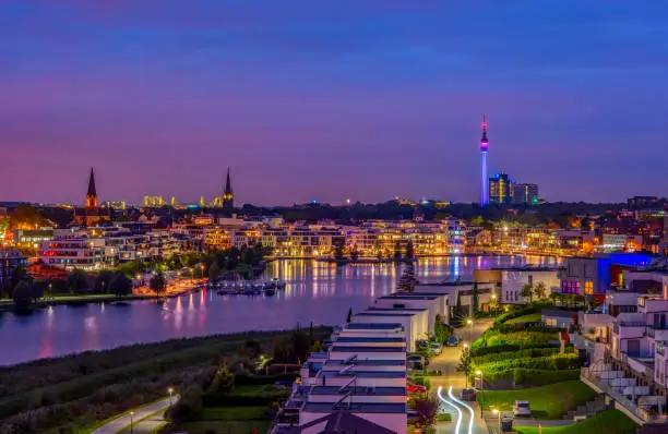 Amazing panoramic view of Phoenix Lake in Dortmund, Germany over city skyline and Florian Tower illuminated at twilight. It is an artificial lake and recreational area on the former steelworks