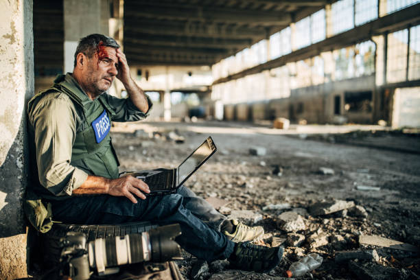 istock Wounded war journalist using laptop in war zone 1183371723