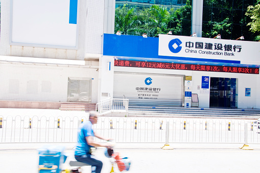 Motorcyclist rides past a local China Construction Bank branch in Futian Business District, Shenzhen - China.