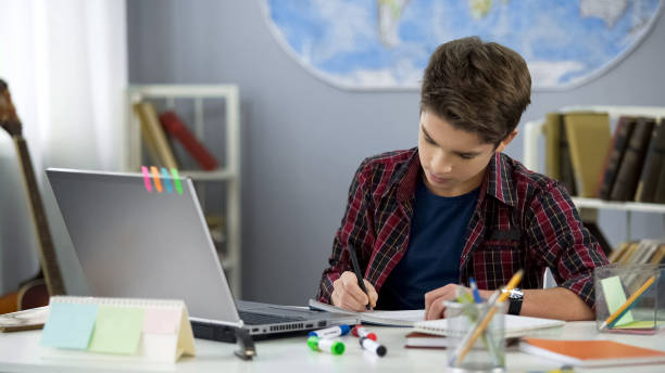 school pupil writing notebook doing home work at table, distance education - homework pencil people indoors imagens e fotografias de stock