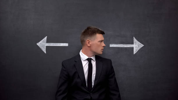istock Confused businessman standing between arrows, choosing right direction, profit 1183376227