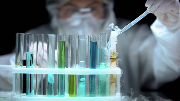istock Scientist dropping sample to liquid boiling in test tube with warning symbol 1183376798