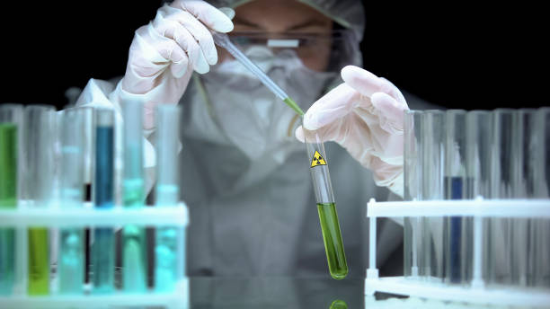 istock Scientist taking sample from tube with ionic radiation sign, mixing with liquid 1183376875