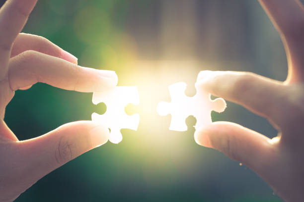 istock Two hands holding a jigsaw puzzle on the evening light detail blur 1183376947