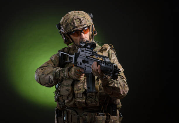 istock a male soldier in military clothes with a weapon on a dark background 1183379708