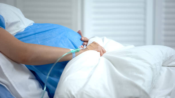 mujer embarazada sosteniendo la manta, sensación de dolor abdominal, riesgo de aborto espontáneo - sección hospitalaria fotografías e imágenes de stock