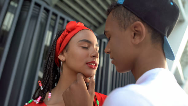 afro-amerykański nastolatek chłopiec z miłością trzyma ładną twarz dziewczyny, próbując całować - couple black american culture kissing zdjęcia i obrazy z banku zdjęć