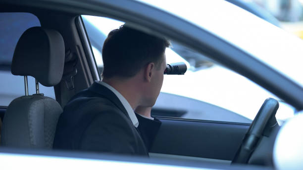 istock Secret spy in car looking through binoculars, confidential information search 1183382093