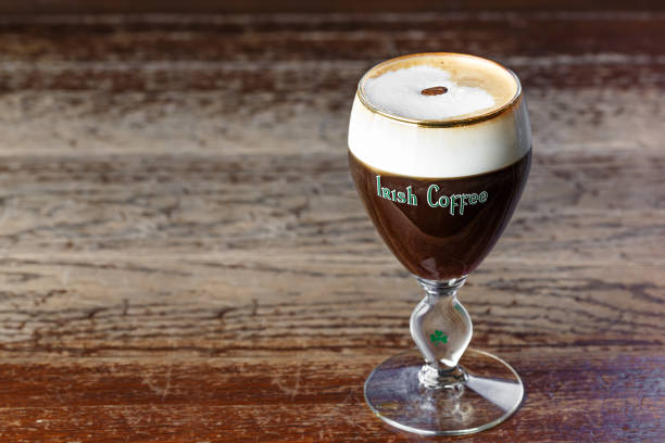 Irish coffee with whiskey. Alcoholic warming cocktail with foam from cream and coffee beans on it.