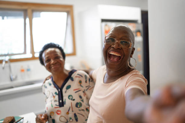 femmes aînées prenant un selfie dans la cuisine - friendship coffee home interior women photos et images de collection
