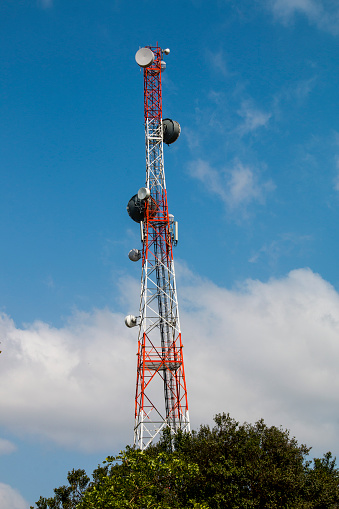 Extremely tall red and white television tower against cloudy blue sky