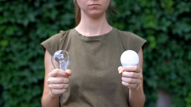 istock Female choosing between LED lamp and light bulb, nature care, energy saving 1183387360