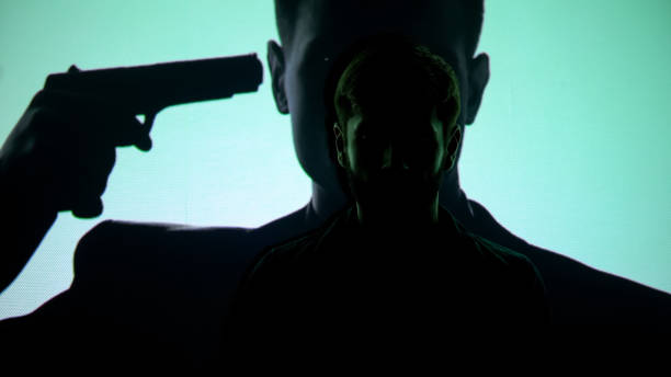 istock Depressed man thinking about suicide, gun near silhouette temple on background 1183387687