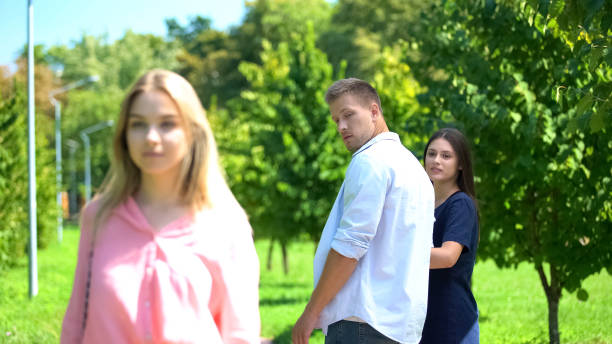 istock Man looking passing blond woman walking park with girlfriend, relations conflict 1183389374
