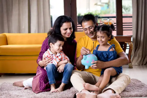 Photo of Parents with children saving money in piggy bank