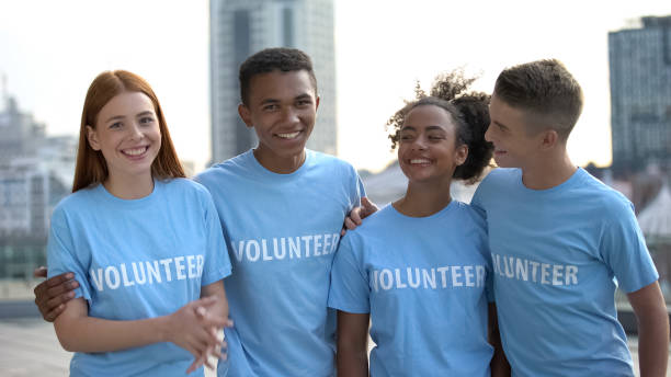 istock Smiling teen group in volunteer t-shirts looking camera, help, social program 1183392026