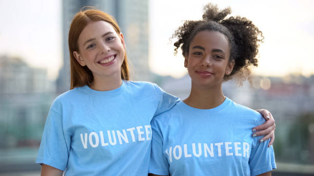 istock Two female volunteers smiling on camera, high school charity program, altruism 1183392037