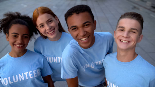 istock Glad college students in volunteer t-shirts looking camera, support togetherness 1183392138