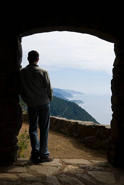 Man Gazing at the World A solitary man looks out over the Oregon coastline from a stone shelter at Cape Perpetua. pacific coast stock pictures, royalty-free photos & images