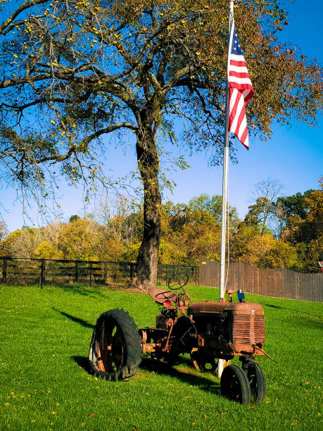 istock Relic Tractor under American Flag highlighted by Fall Leaf Colors 1183394412