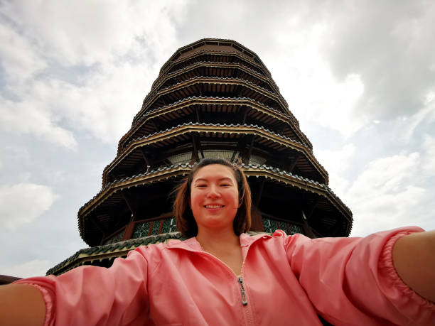 A female adult is enjoing taking selfie at Leaning Clock Tower, the famous tourist destination in Malaysia.