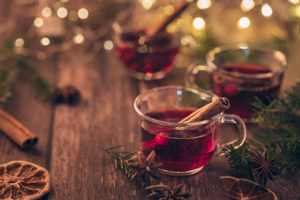 Mulled wine, glühwine or scandinavian glögg. Three cups of warm winter drink for christmas. Mulled wine, glühwine or scandinavian glögg. Three cups of warm winter drink for christmas. On a dark brown wooden table. With cozy string lights in the background. mulled wine photos stock pictures, royalty-free photos & images
