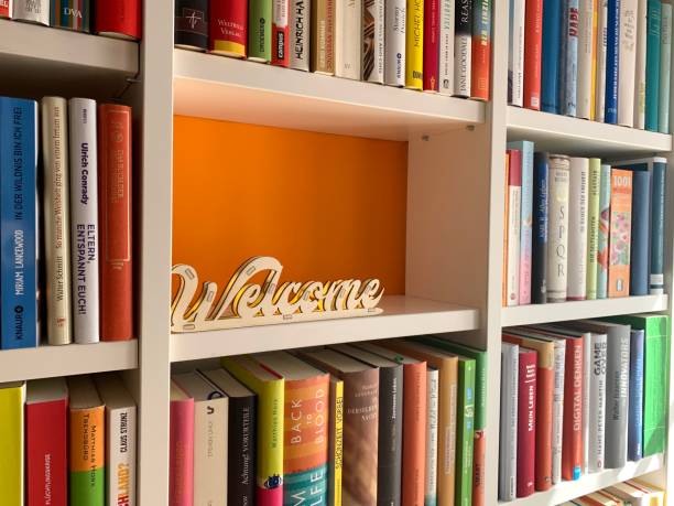 multi colored books in shelves and a welcome sign in empty part - library book shelf generic imagens e fotografias de stock